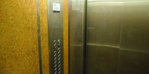 Winda z grawerowaną tabliczką pięter i numerów mieszkań przypominającą PKiN
