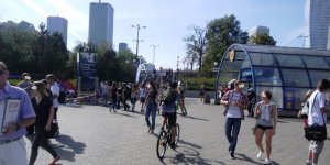 Rowerzysta na chodniku wśród pieszych przed stacją Metro Centrum