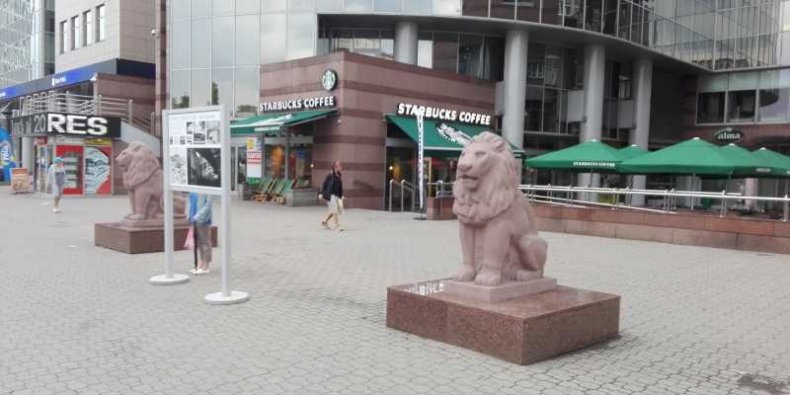 Symbole Mokotowa. Pomiędzy mokotowskimi lwami stoi plansza z fotografiami i opisem Kina Moskwa