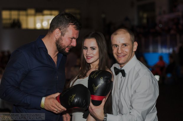 Łukasz Landowski wręcza zwtcięzcy licytacji rękawice z autografami.
