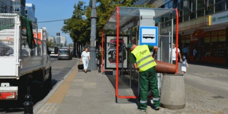 Opróżnianie kosza na przystanku autobusowym w w centrum Warszawy