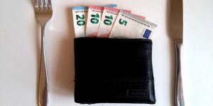Pieniądze w portfelu na stole między sztućcami