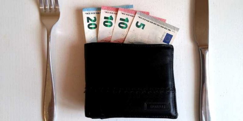 Pieniądze w portfelu na stole między sztućcami