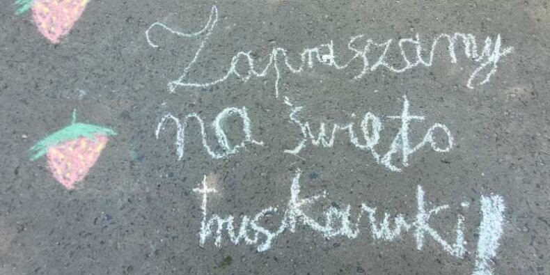 Zaproszenie na Święto Truskawki. Napis kredą na asfalcie.