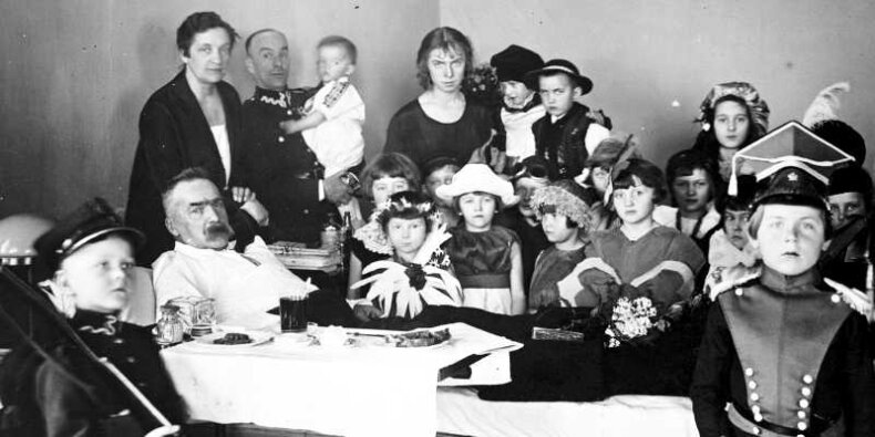 Pięcioletni Zbigniew Wójcik w przebraniu (pierwszy z lewej) obok Józefa Piłsudskiego. Zdjęcie podczas wizyty u marszałka dzieci z belwederskiego przedszkola "Rodziny Wojskowej" w 1927 roku. (NAC, fot. Witold Pikiel).