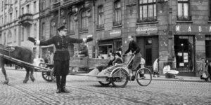 Polski policjant kieruje ruchem na skrzyżowaniu ul. Nowy Świat i Książęcej. Widoczny zakład pogrzebowy Mieczysława Adamskiego i riksza. Październik 1940 r .
