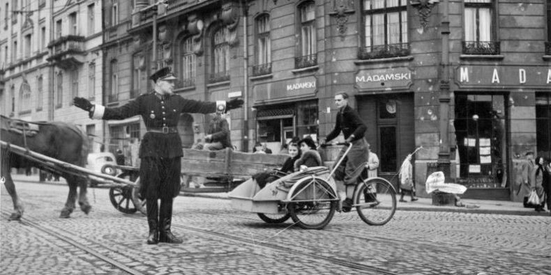 Polski policjant kieruje ruchem na skrzyżowaniu ul. Nowy Świat i Książęcej. Widoczny zakład pogrzebowy Mieczysława Adamskiego i riksza. Październik 1940 r .