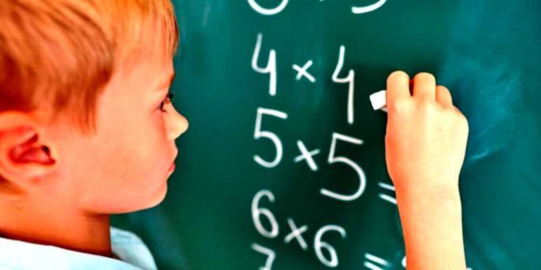 Chłopiec przy tablicy rozwiązuje zadanie z matematyki