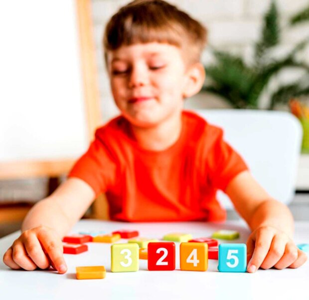 Zabawa z cyframi zachętą do poznawania matematyki (chłopiec ustawia klocki z cyframi)