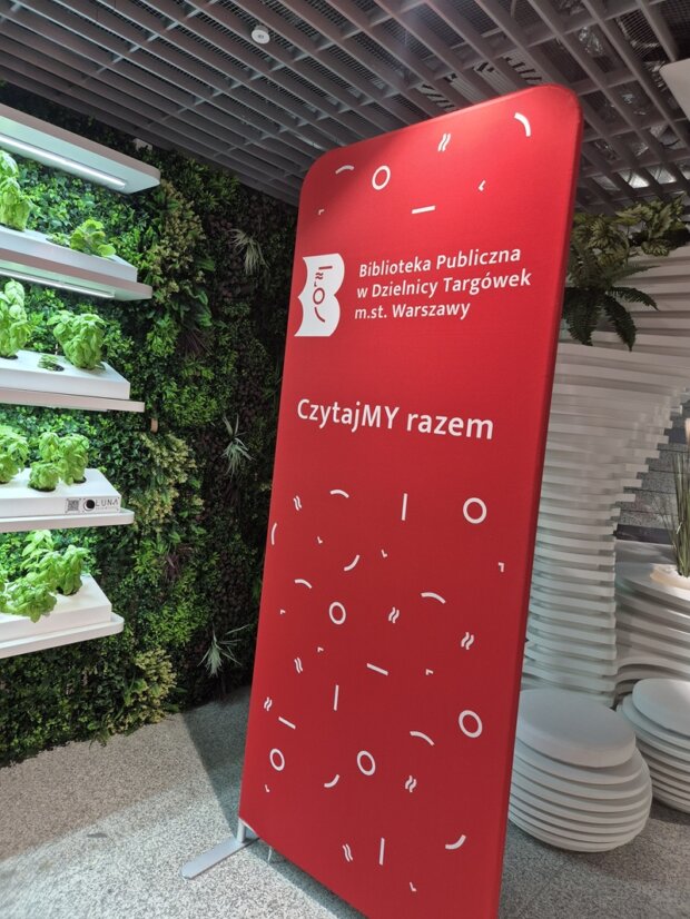 Bilboard Biblioteki wśród kwiatów